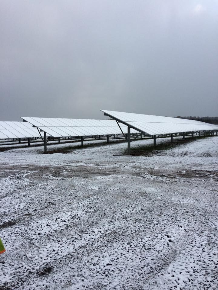 A row of solar panels sitting on top of a snow covered field.