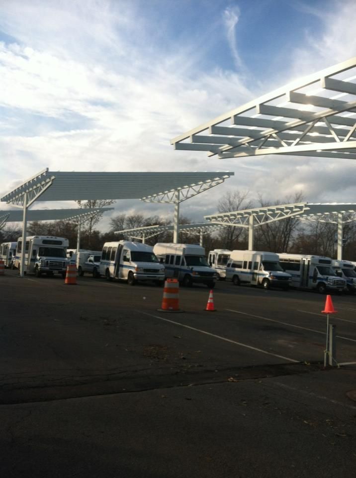 A parking lot with a lot of vehicles parked under umbrellas