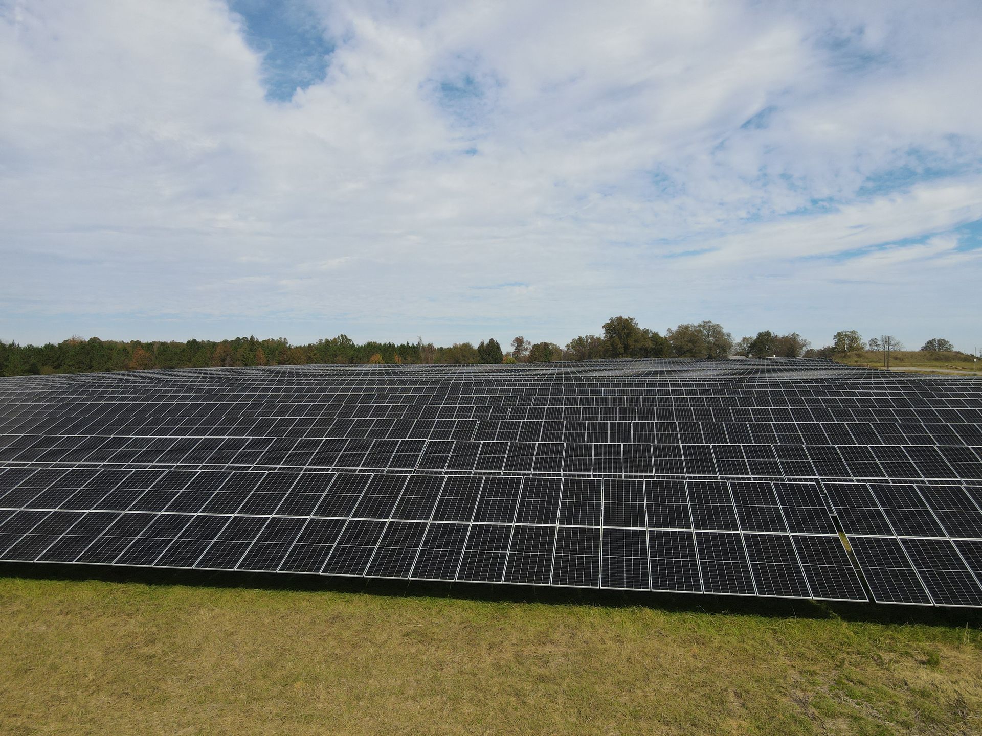 A row of solar panels sitting on top of a grassy field.