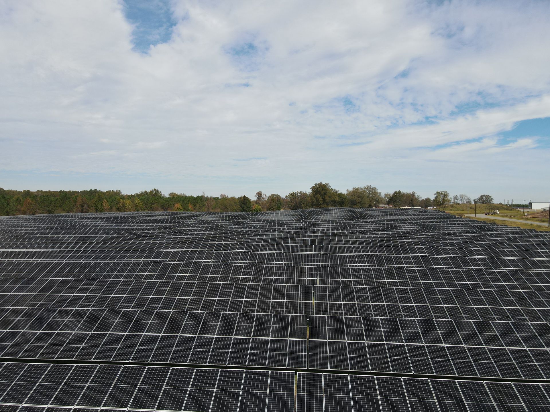 A large field of solar panels against a cloudy sky