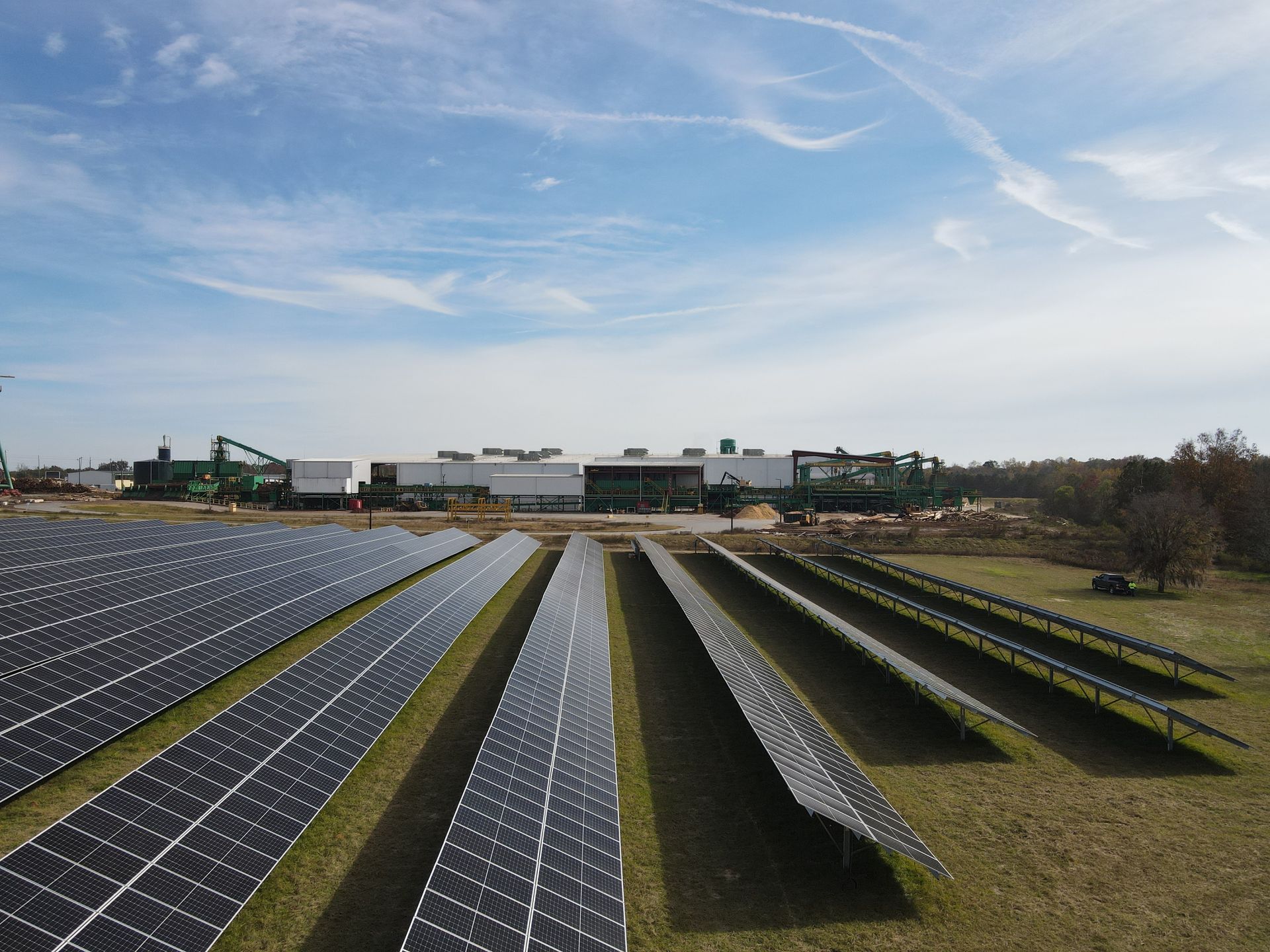 Rows of solar panels in a field with a building in the background