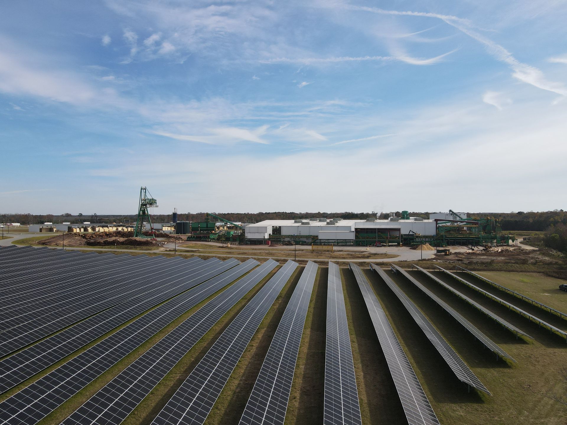 A row of solar panels in a field with a building in the background.