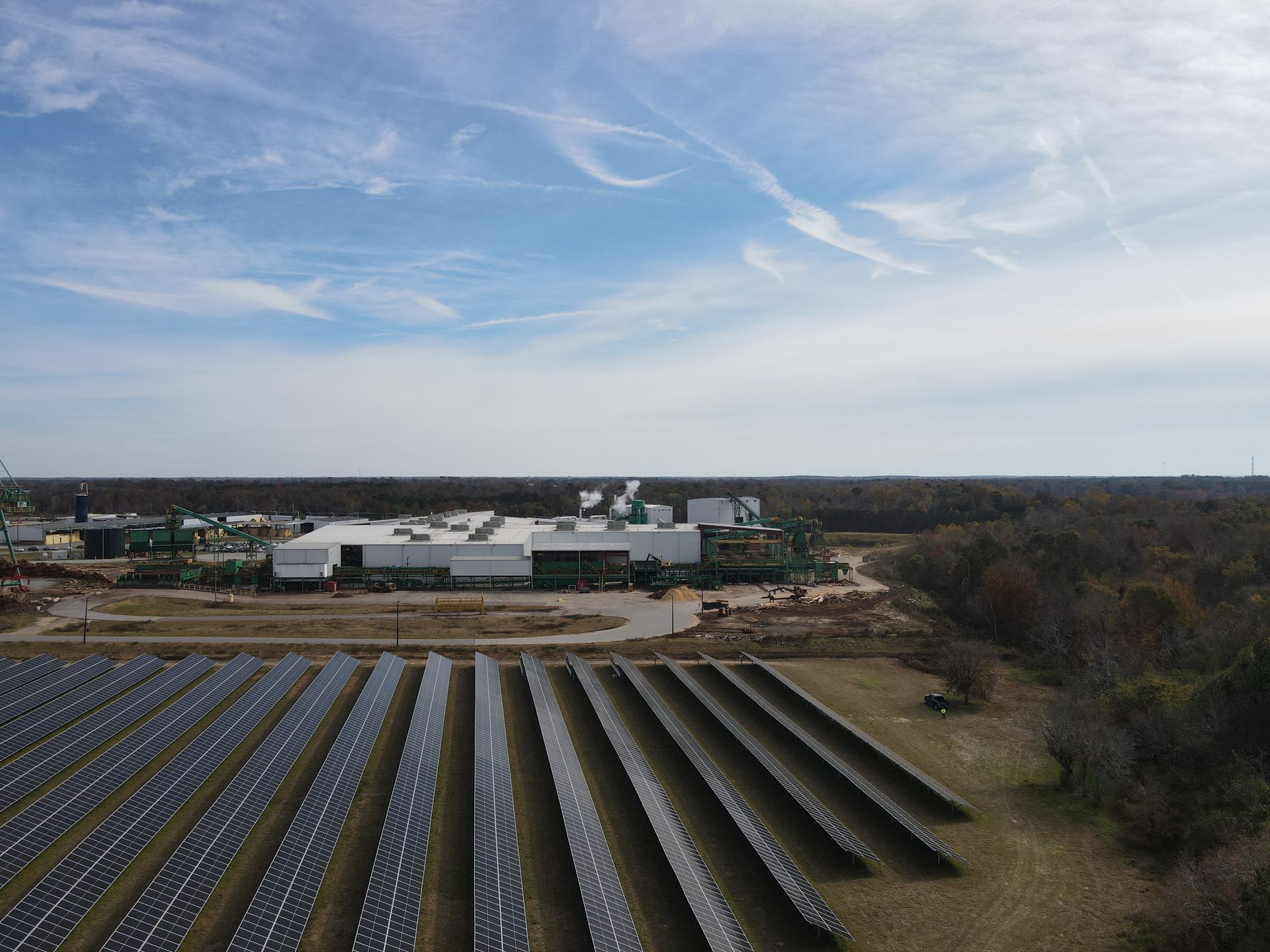 An aerial view of a solar farm with a building in the background.