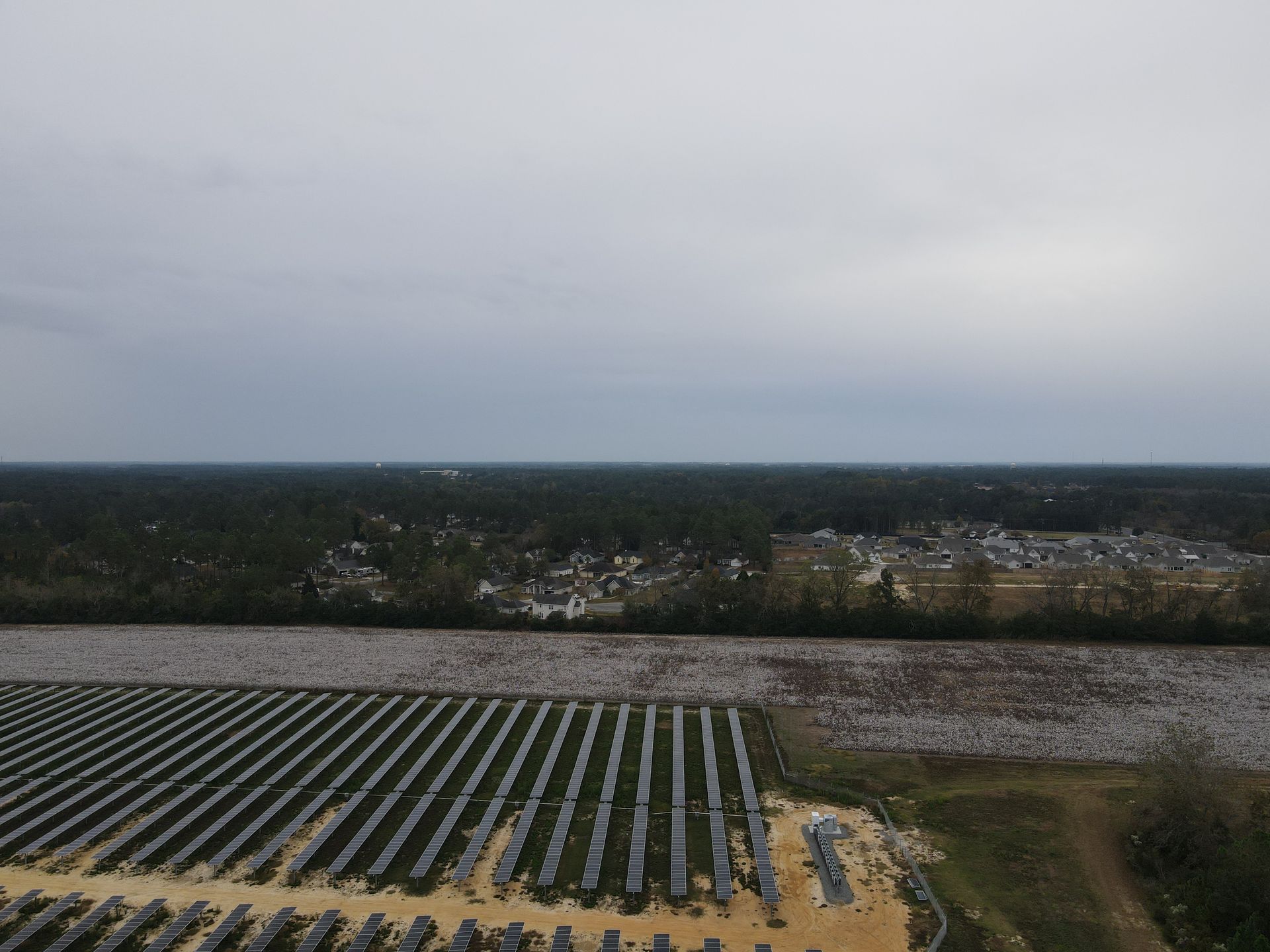 An aerial view of a solar farm with a cloudy sky in the background