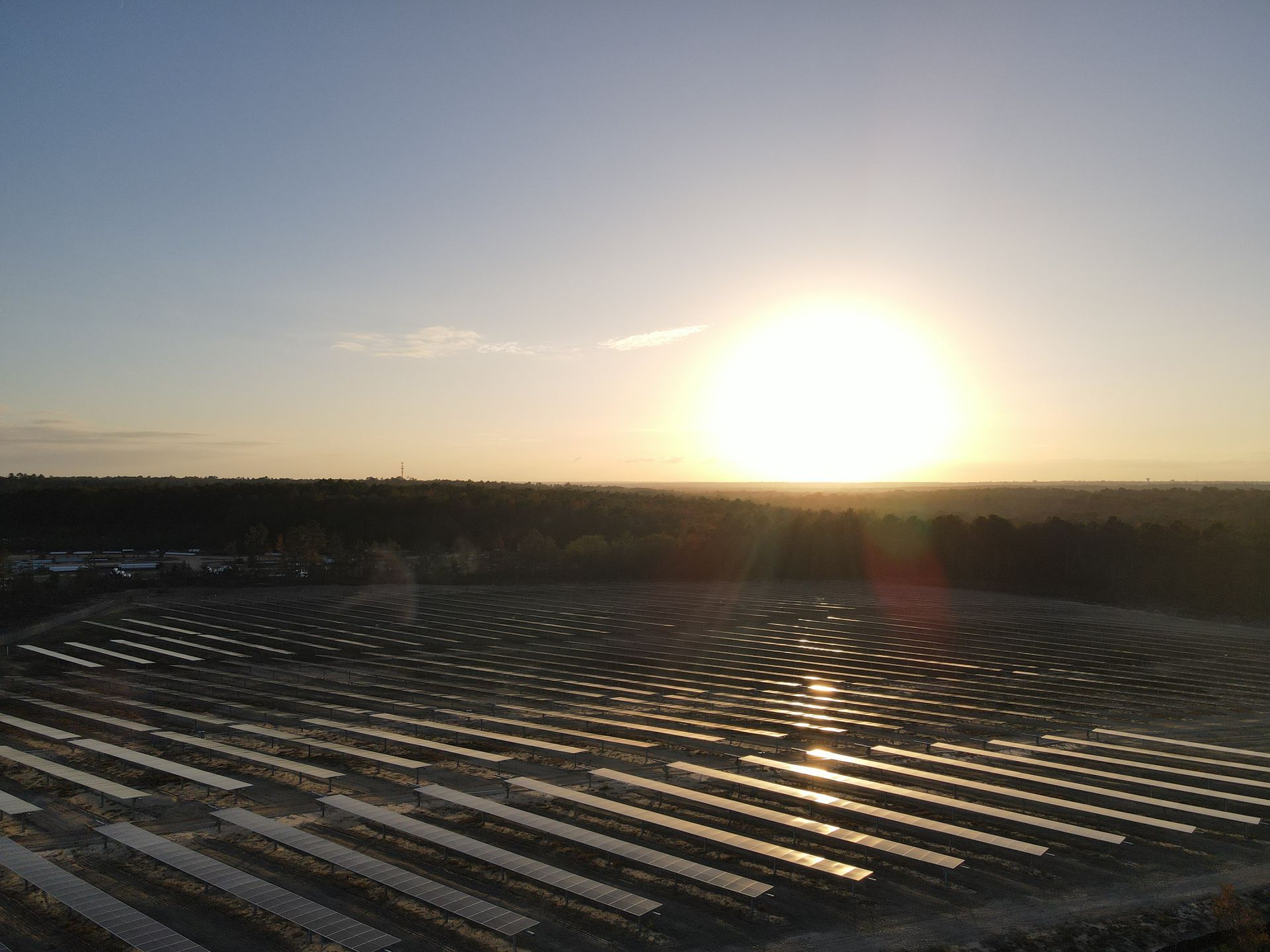 The sun is setting over a large field of solar panels.