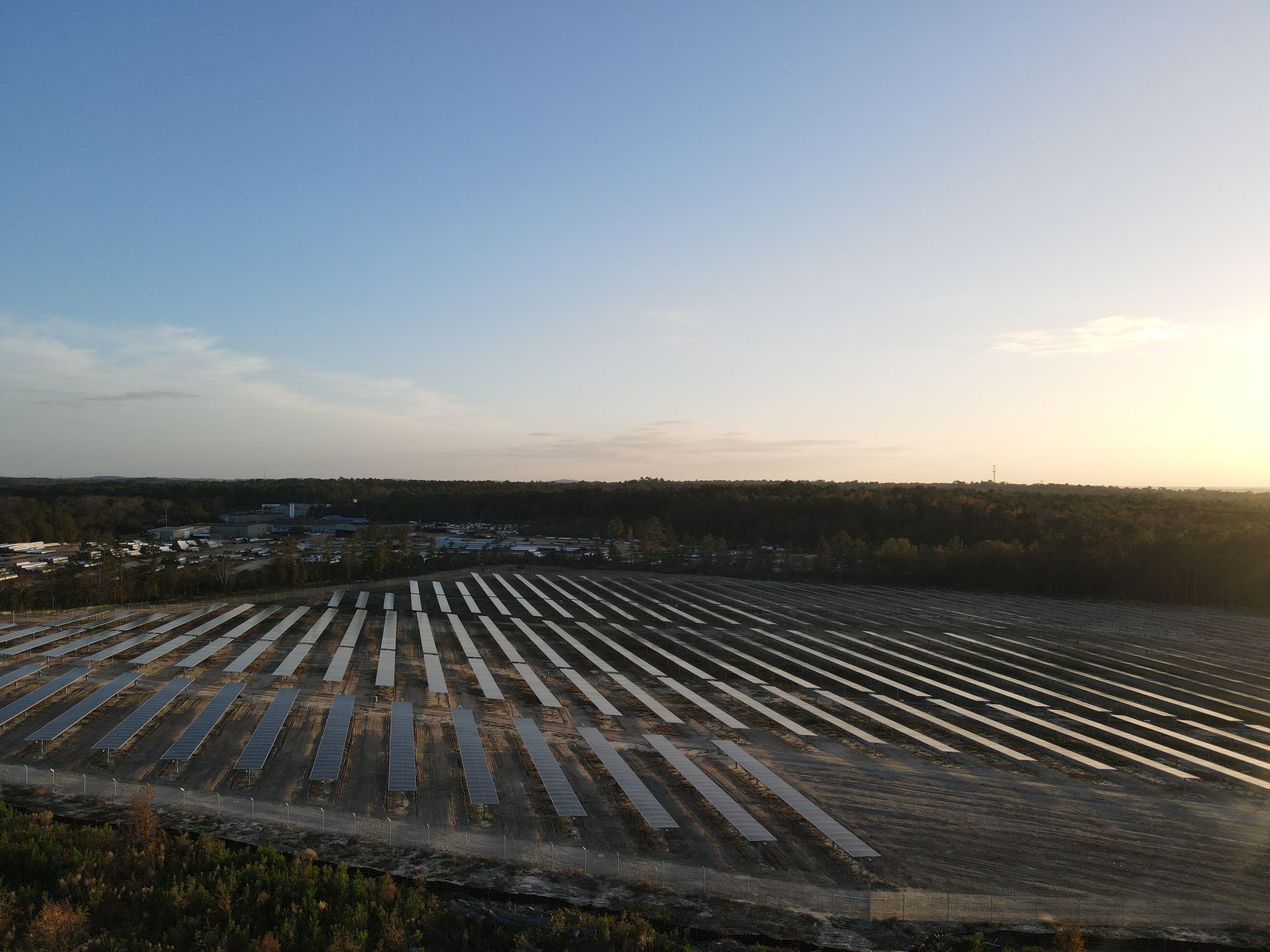A large field of solar panels sitting on top of a dirt hill.