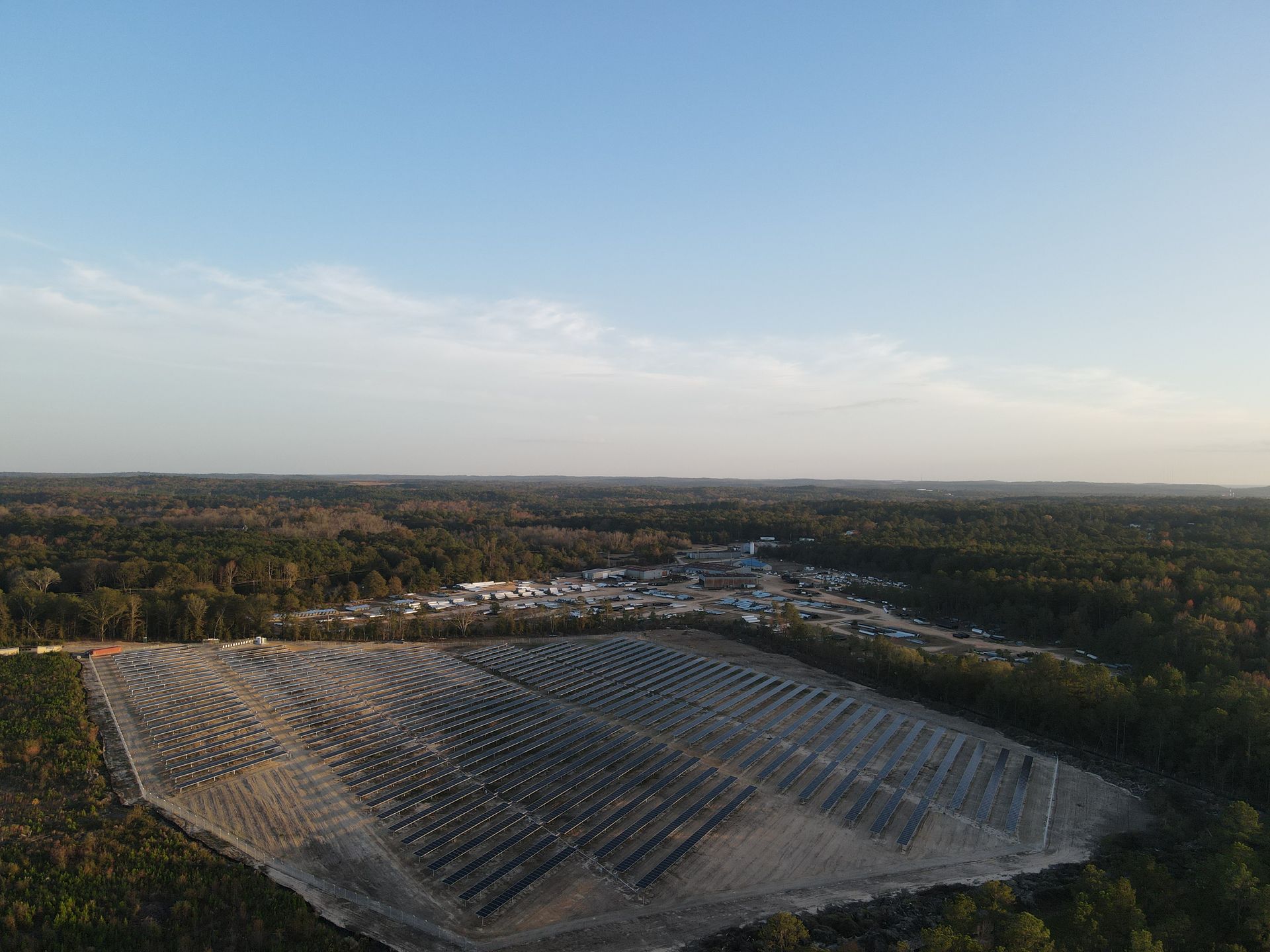 An aerial view of a large solar farm in the middle of a forest.