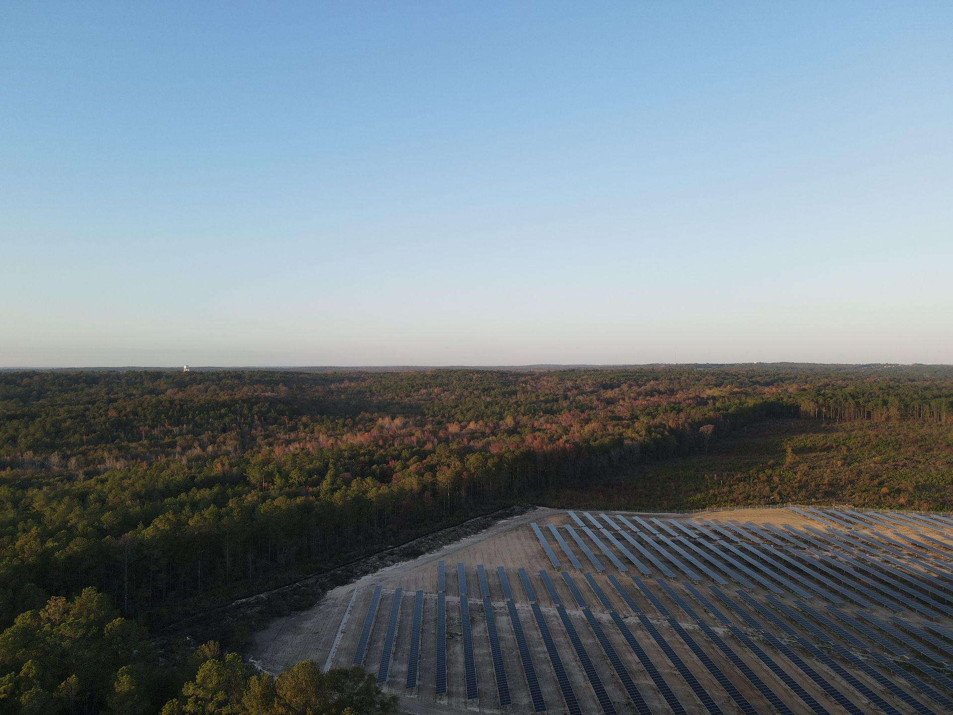An aerial view of a solar farm in the middle of a forest.