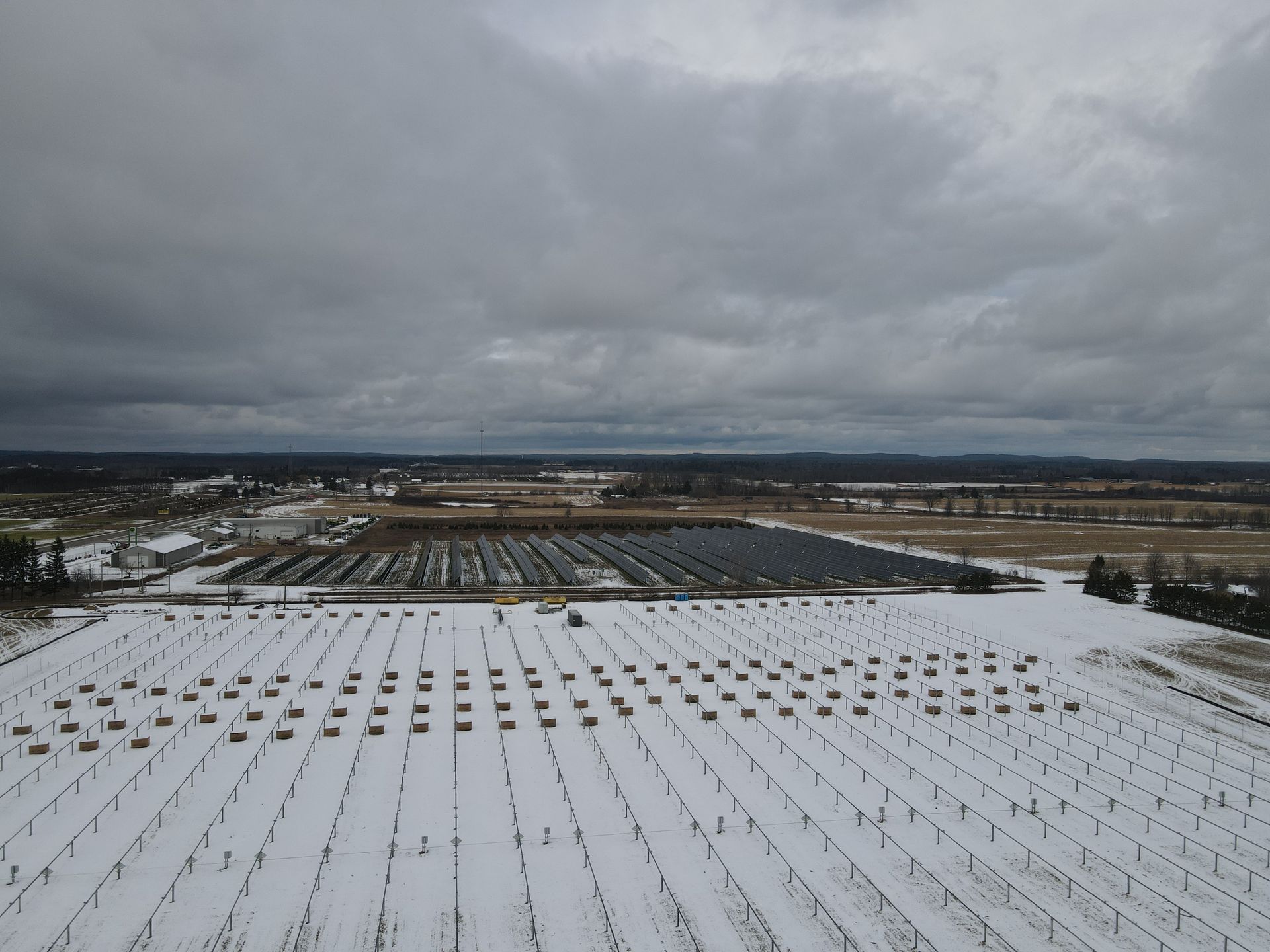 An aerial view of a snowy field with rows of solar panels
