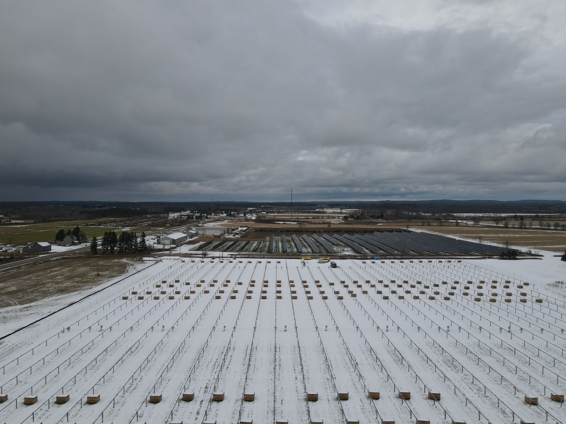 An aerial view of a snow covered field with solar panels.