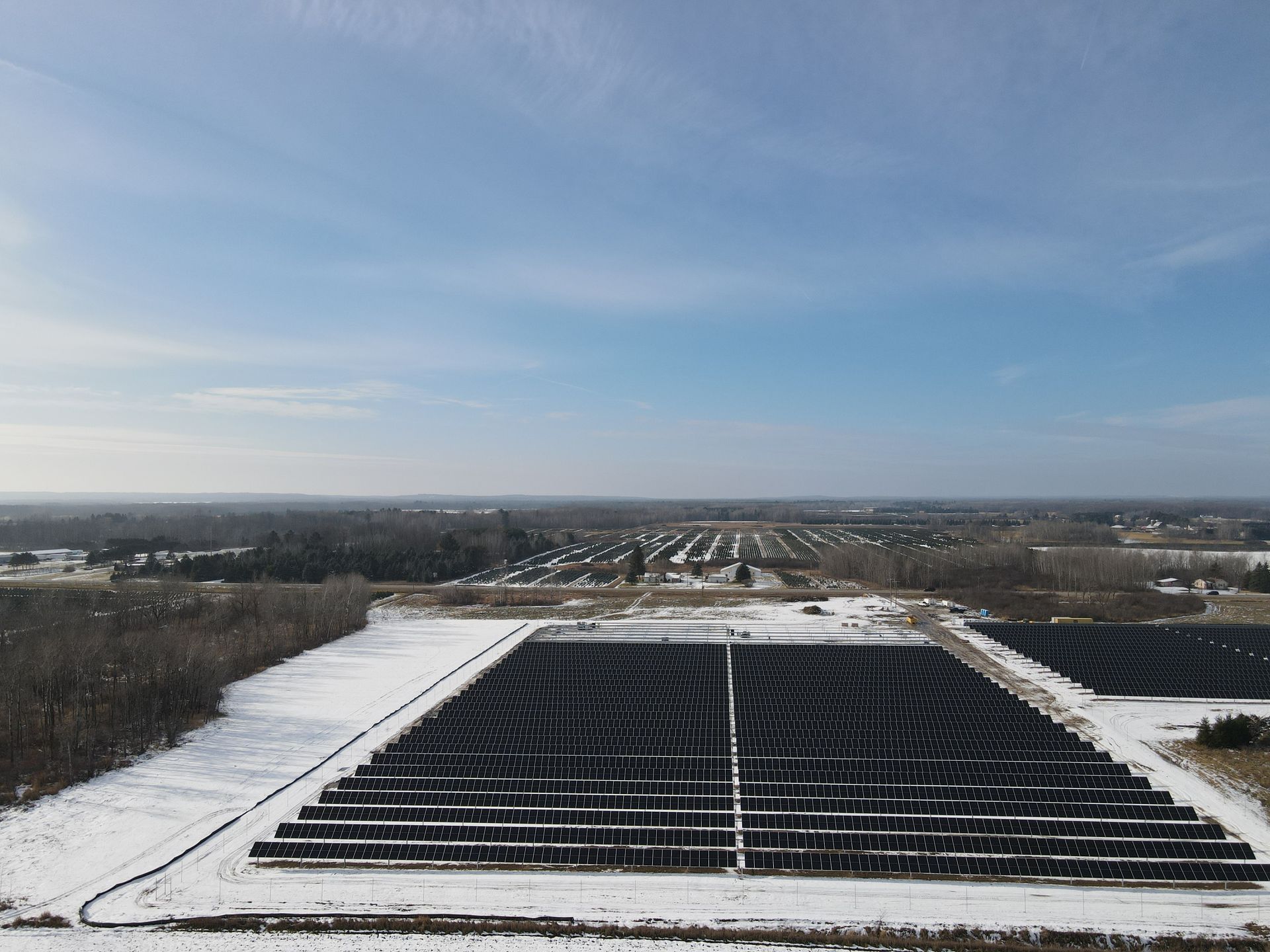 An aerial view of a solar farm in the snow.