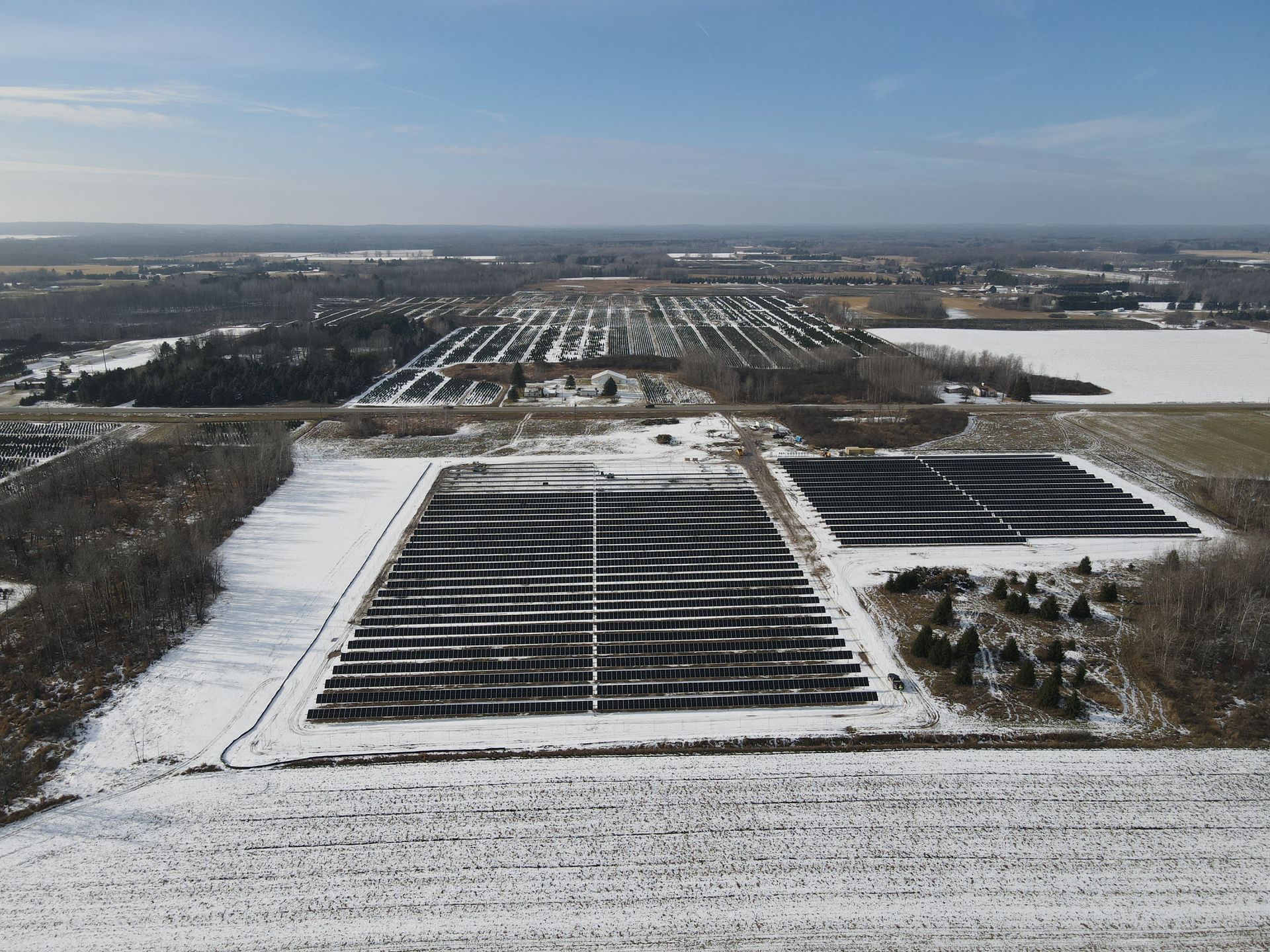 An aerial view of a snowy field with a lot of trees in the background
