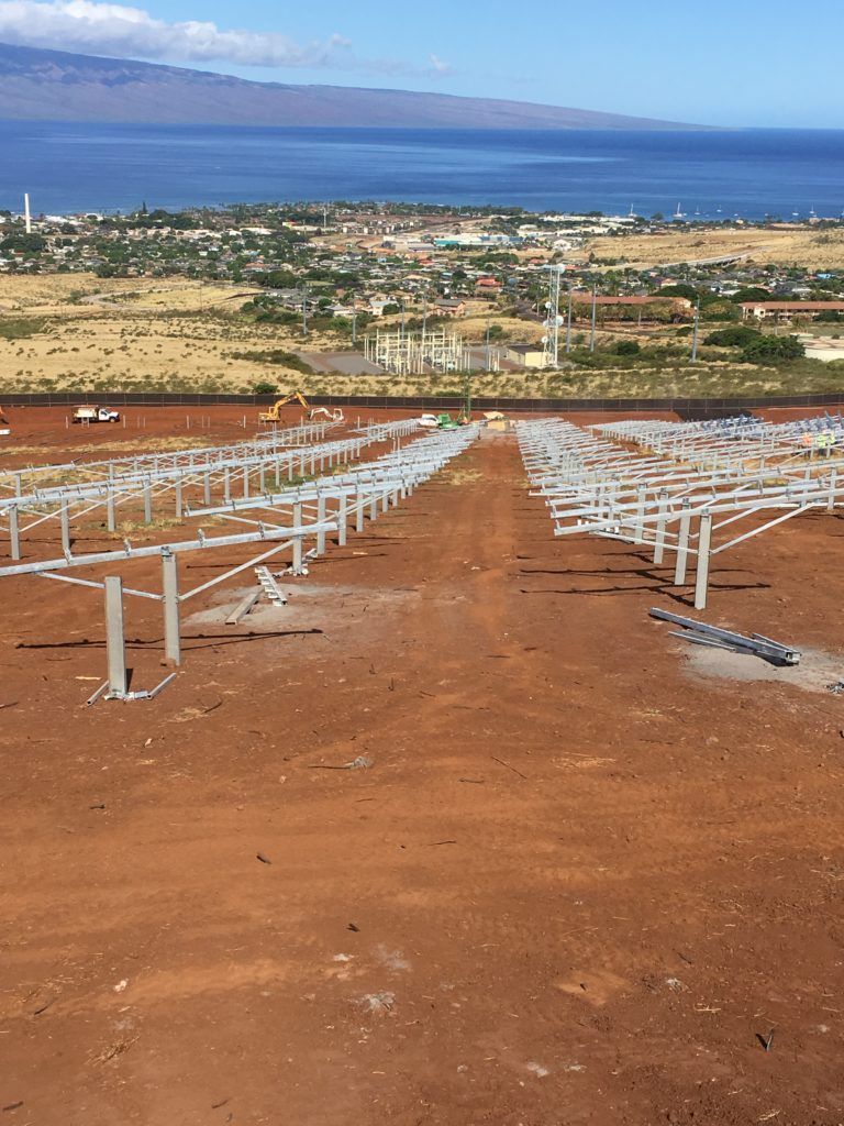 A row of solar panels are sitting on top of a dirt hill.