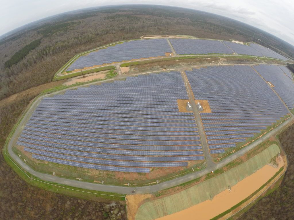 An aerial view of a large solar farm in the middle of a forest.