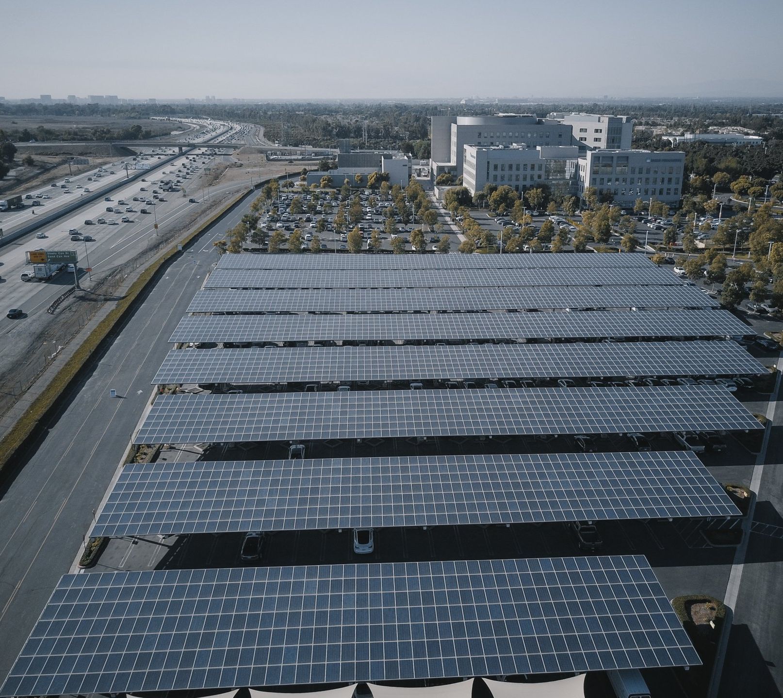 An aerial view of a parking lot with lots of solar panels that also act as shading for the lot