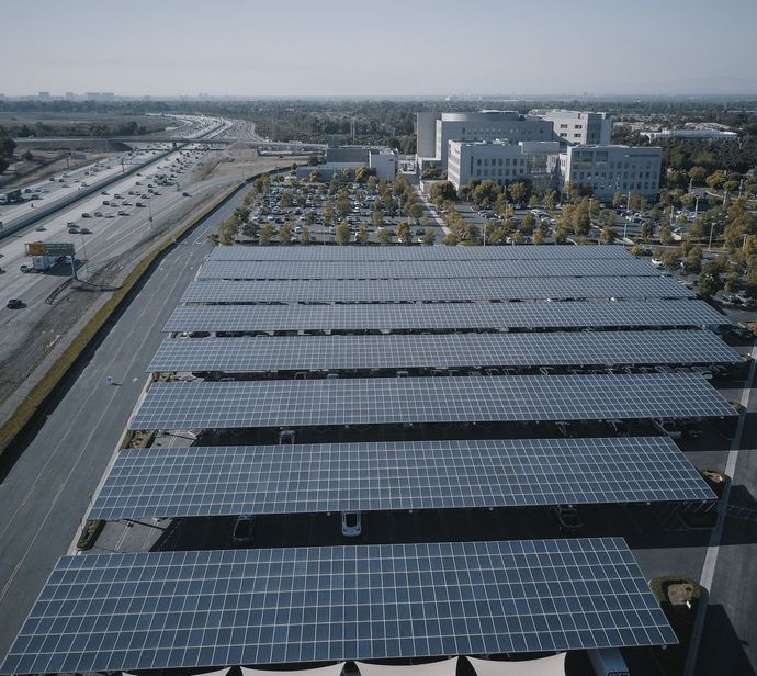 An aerial view of a parking lot with lots of solar panels that also act as shading for the lot