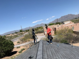 Two men are working on the roof of a house.