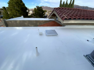 A white roof with a red tile roof in the background.