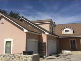 A house with a brown roof and a pink facade