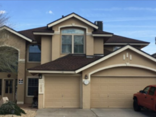 A large tan house with a red truck parked in front of it