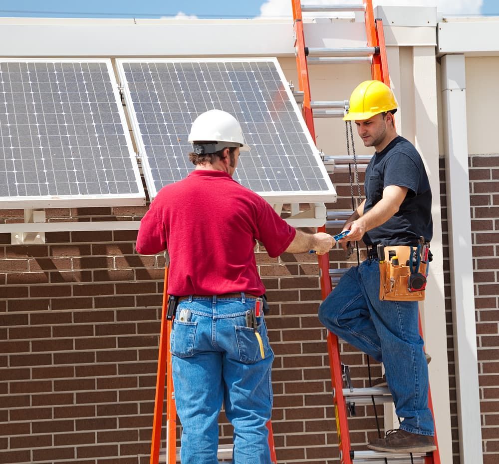 Two Men Are Installing Solar Panels On A Brick Building — Evolution Solar Kingaroy in Blackbutt, QLD