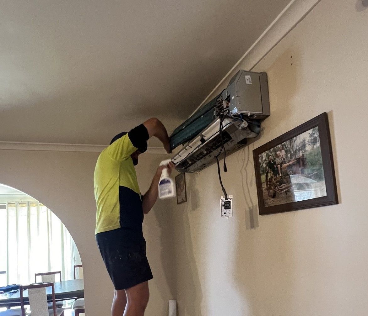 A Man Is Fixing An Air Conditioner On The Wall — Evolution Solar Kingaroy in Kingaroy, QLD