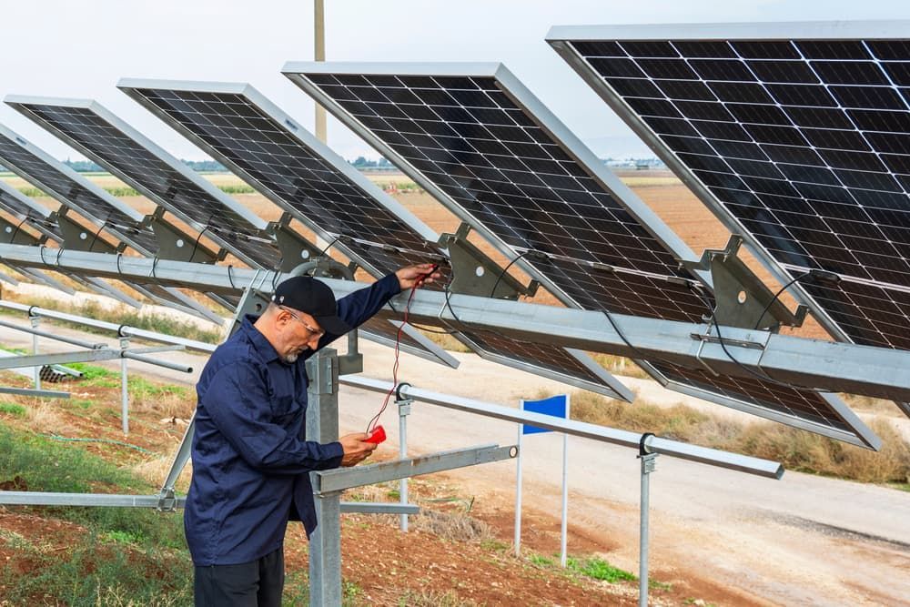 A Man Is Working On A Solar Panel In A Field — Evolution Solar Kingaroy in Yarraman, QLD