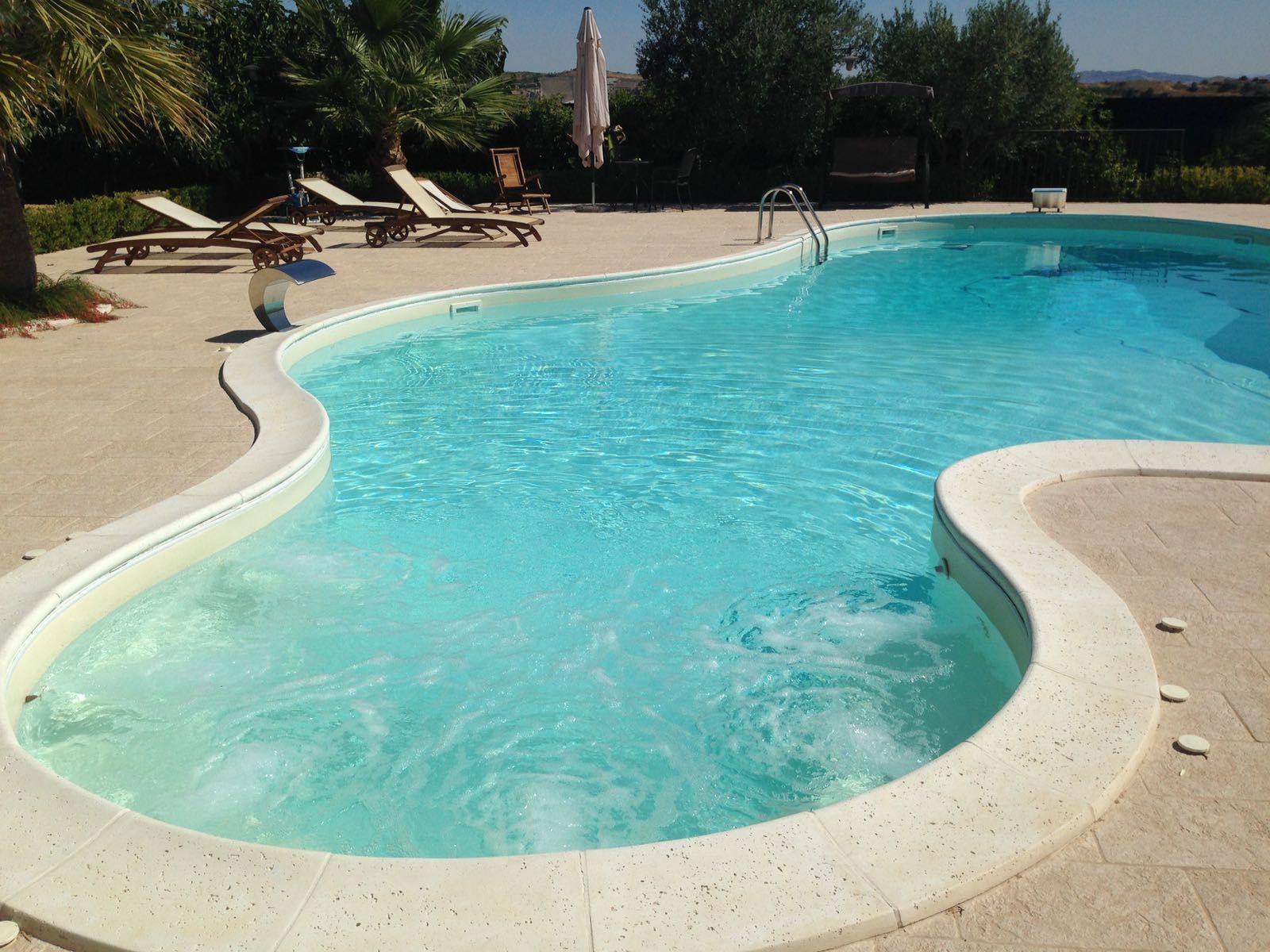 Una grande piscina con sedie e ombrelloni intorno