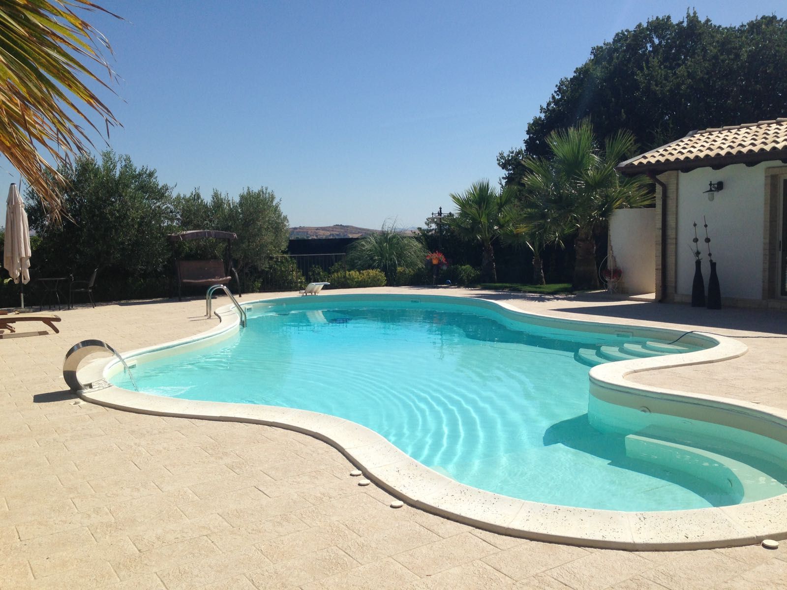 Una grande piscina circondata da palme in una giornata di sole