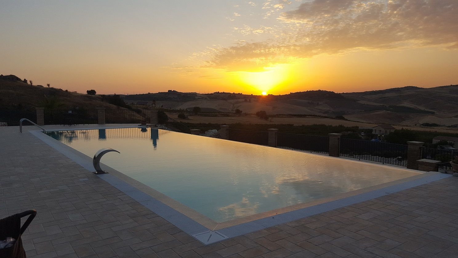 Una grande piscina con un tramonto sullo sfondo.