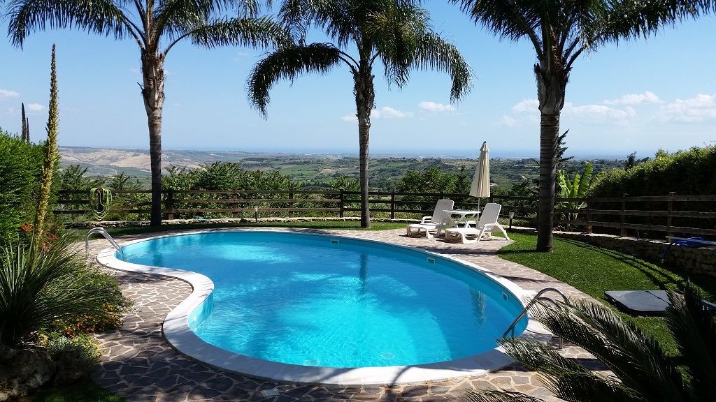 Una grande piscina circondata da palme e sedie