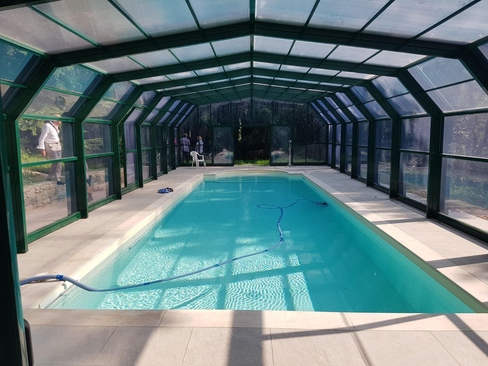 Una grande piscina è coperta da un tetto verde.