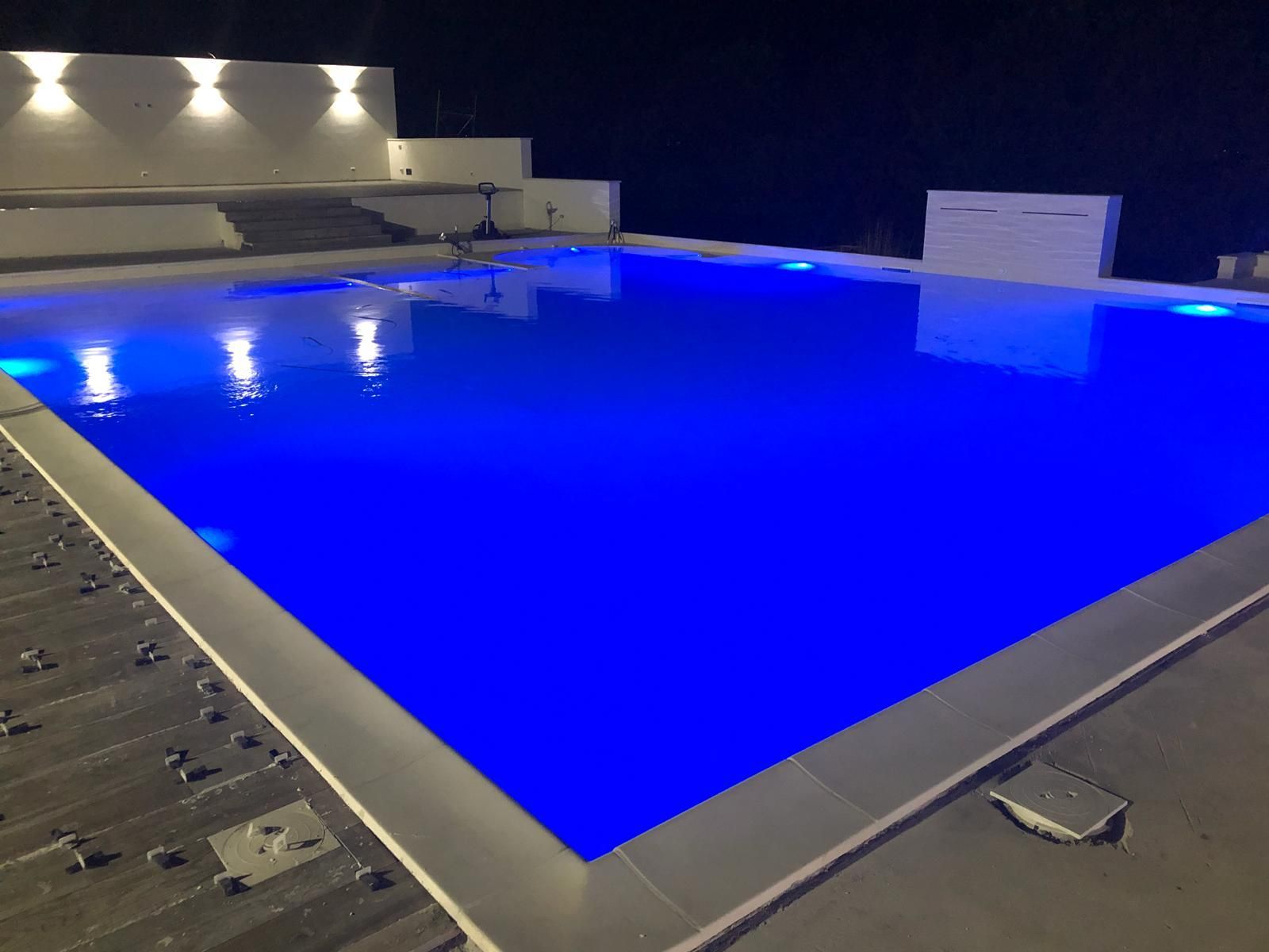 Una grande piscina è illuminata di notte con luci blu