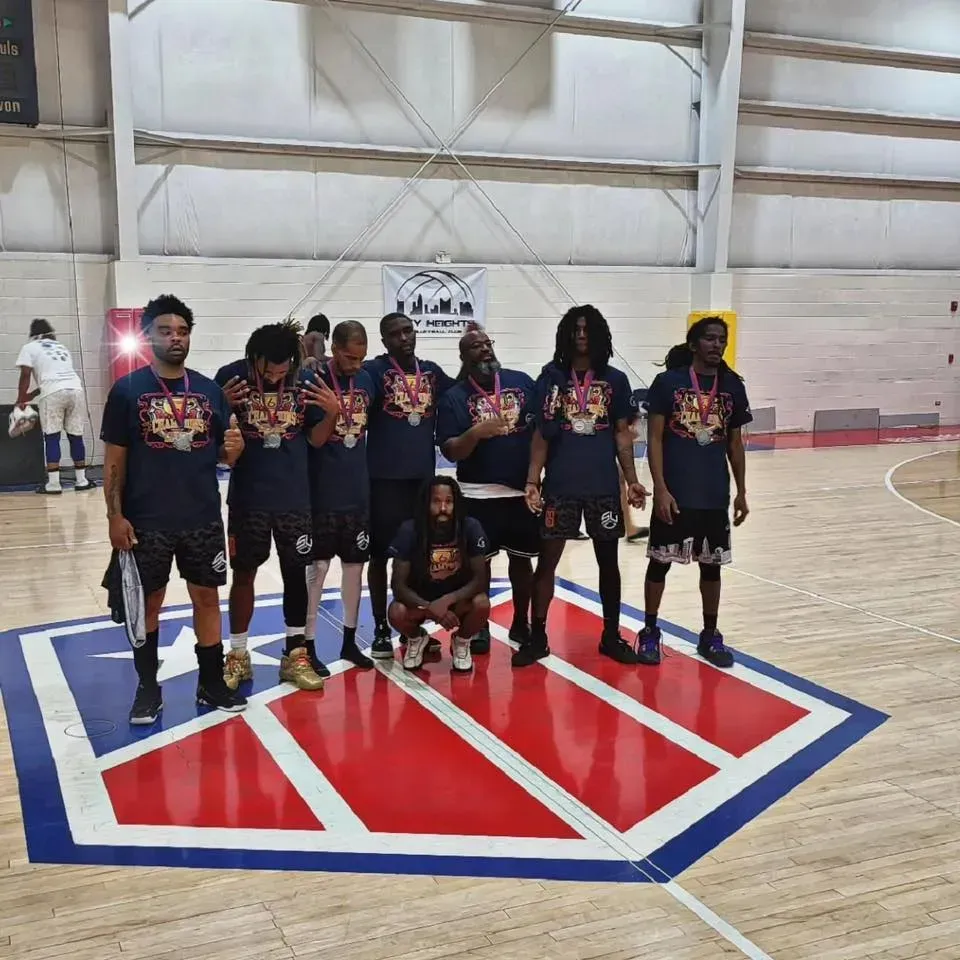 A group of men are posing for a picture on a basketball court