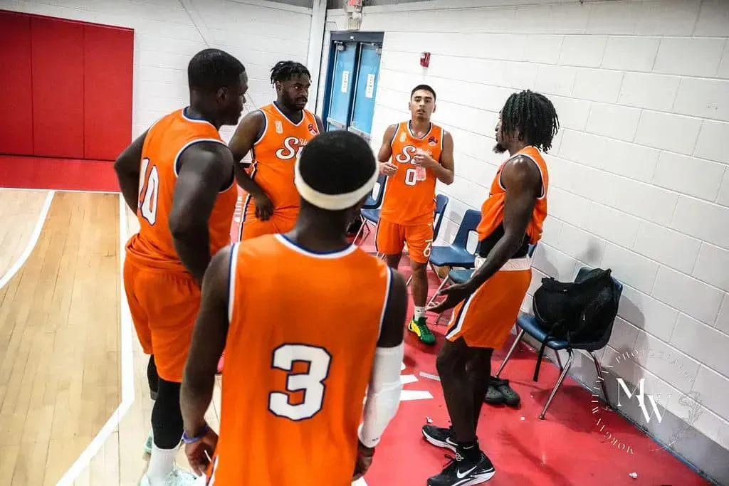 A group of basketball players are standing in a huddle on the court.