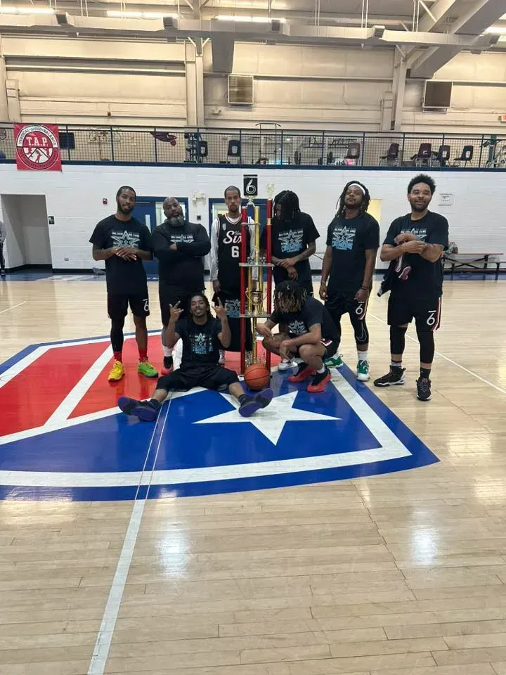 A group of men are posing for a picture on a basketball court.