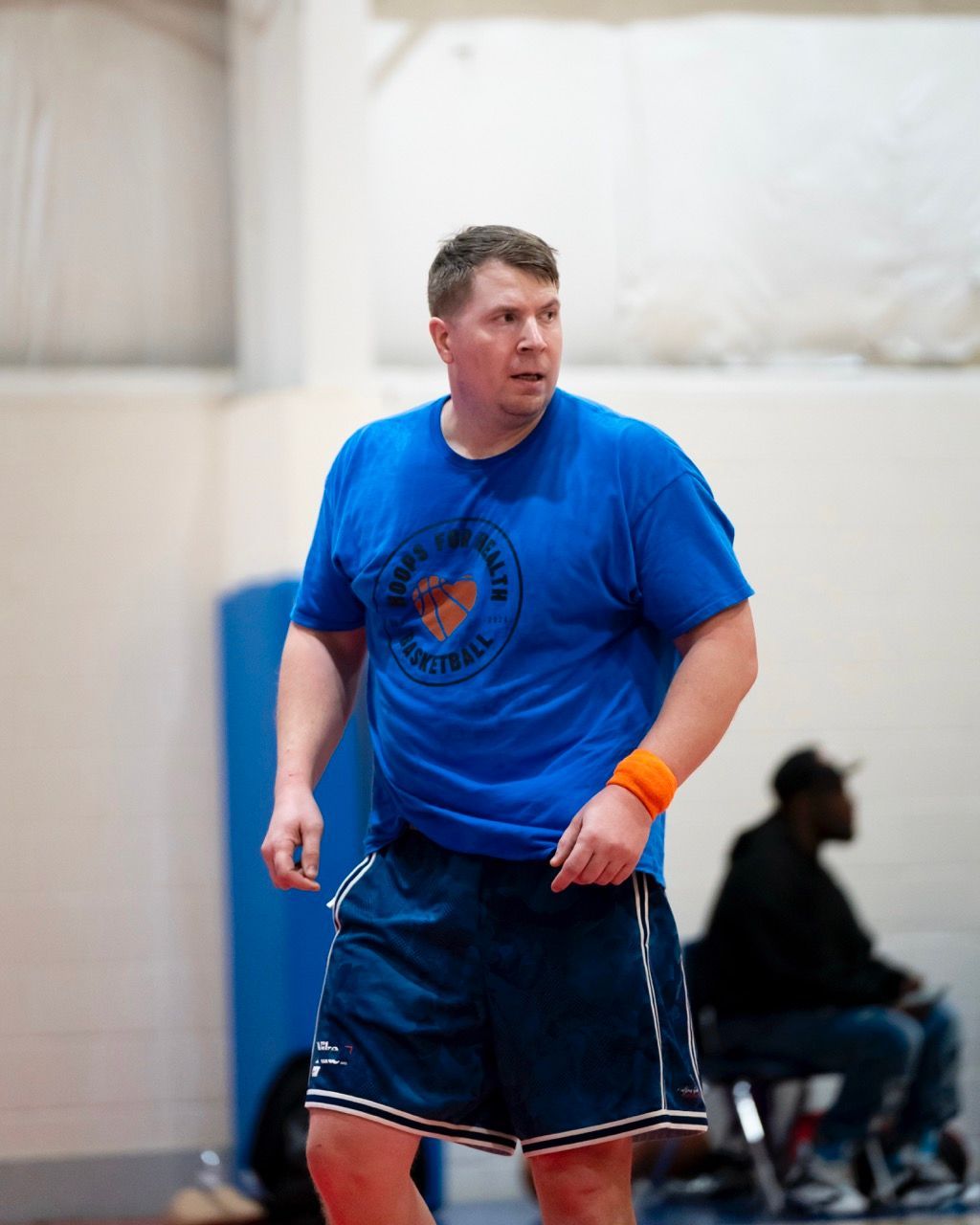 A man in a blue shirt and shorts is standing in a gym