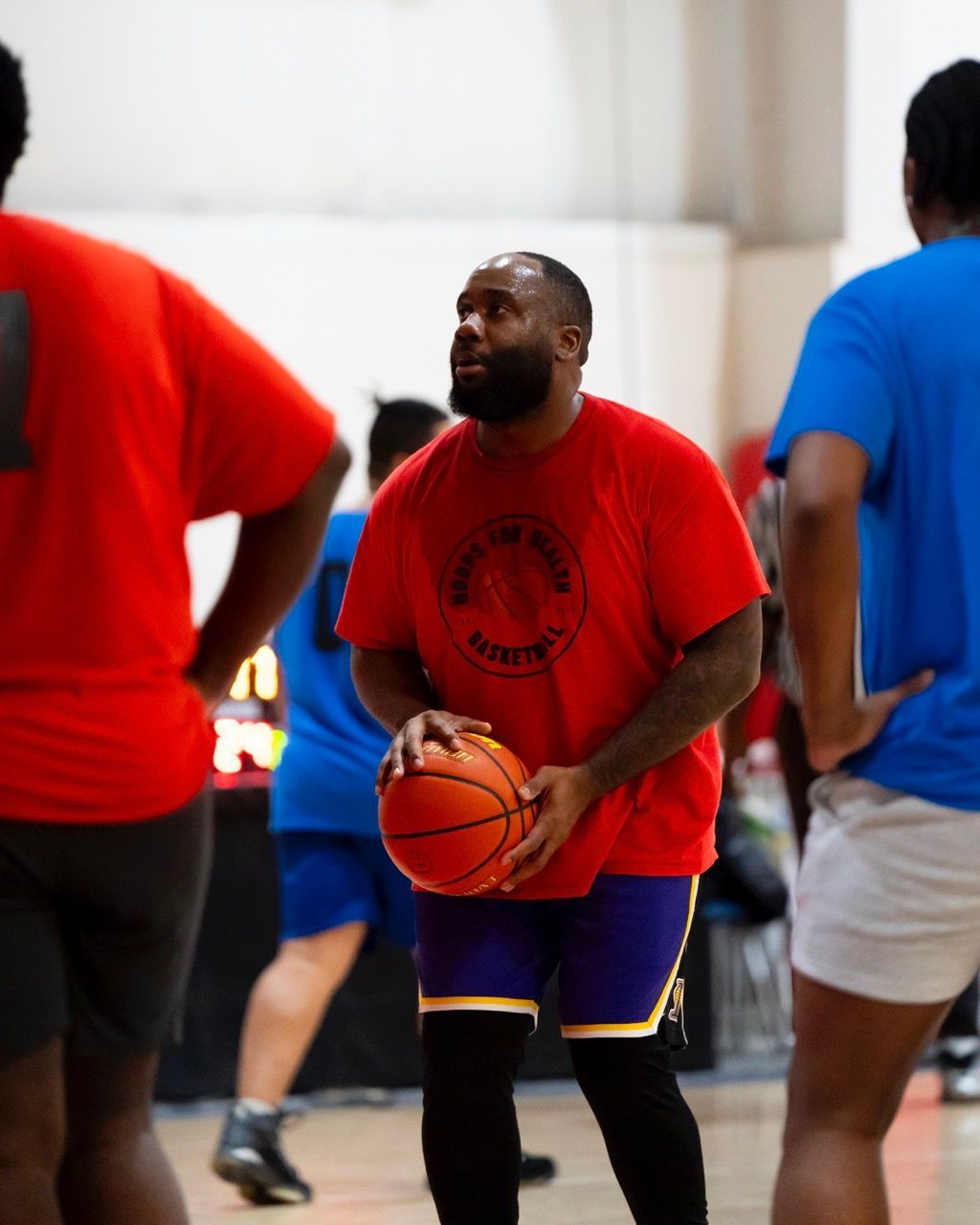 A man in a red shirt is holding a basketball