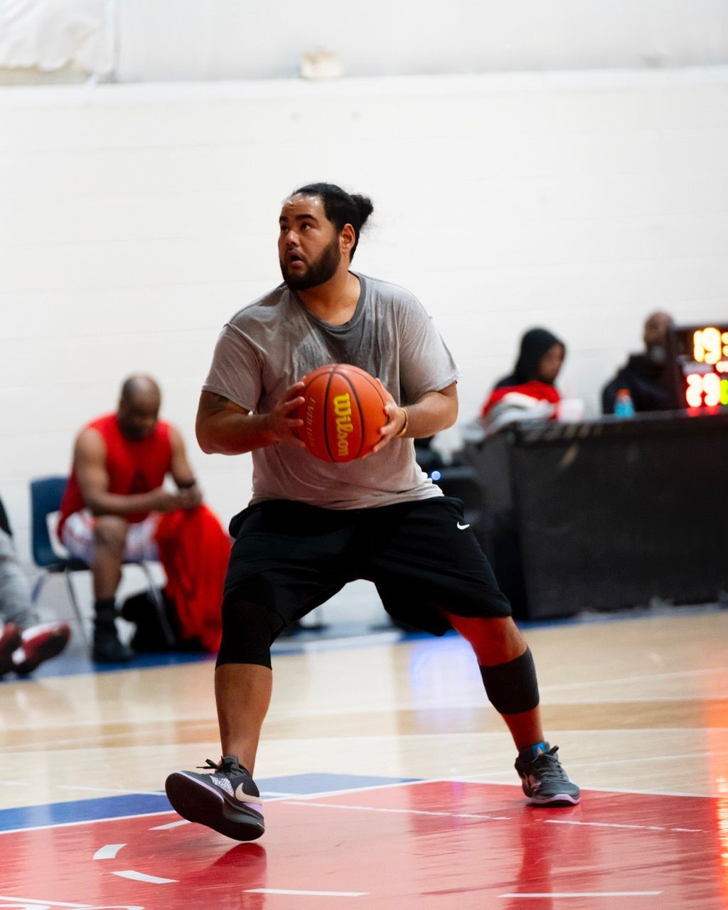 A man holding a wilson basketball on a basketball court
