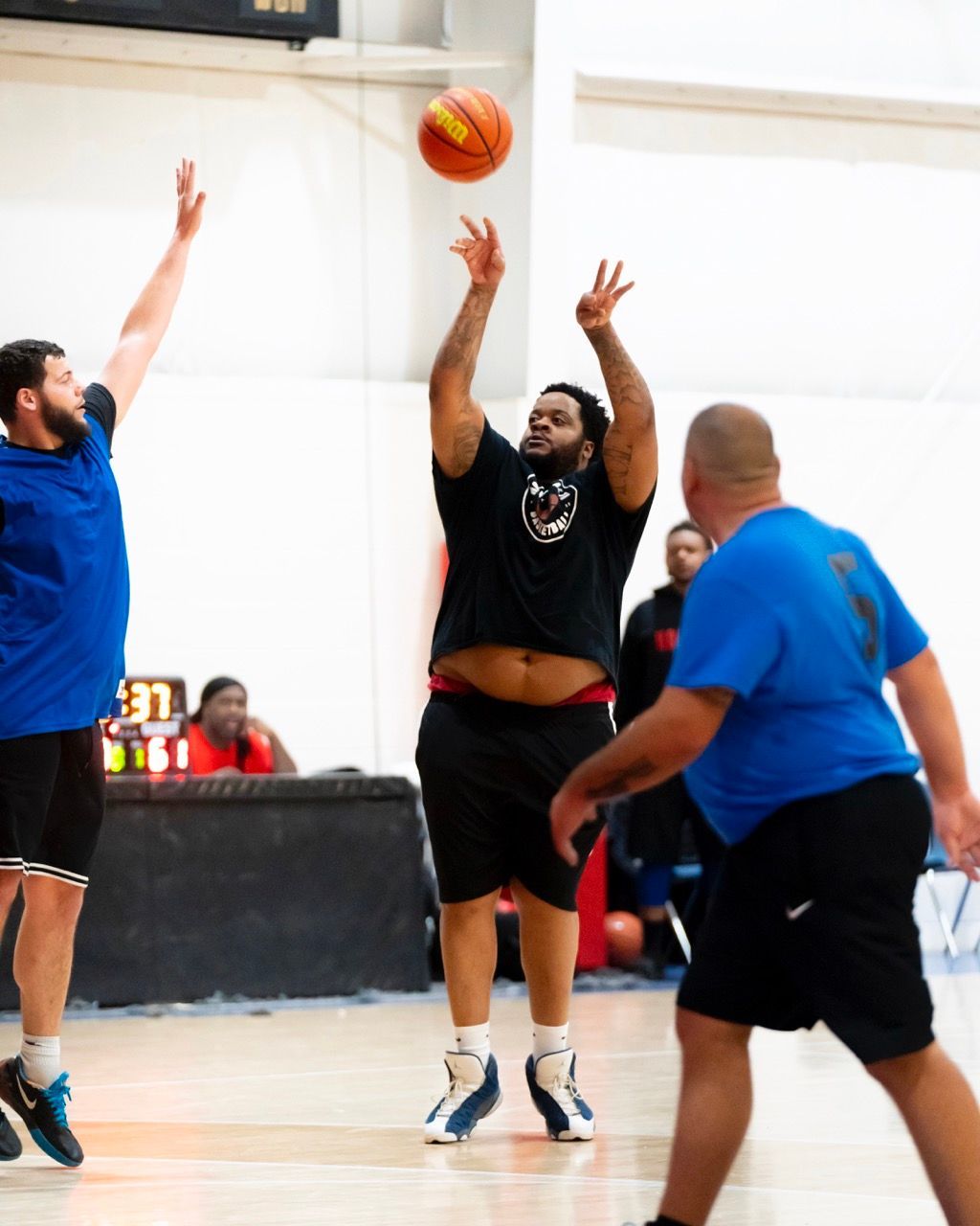 A man in a black shirt is throwing a basketball in the air