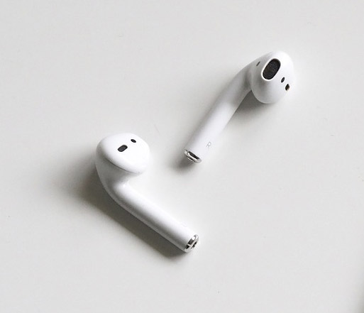 A pair of white airpods are sitting on a white surface.