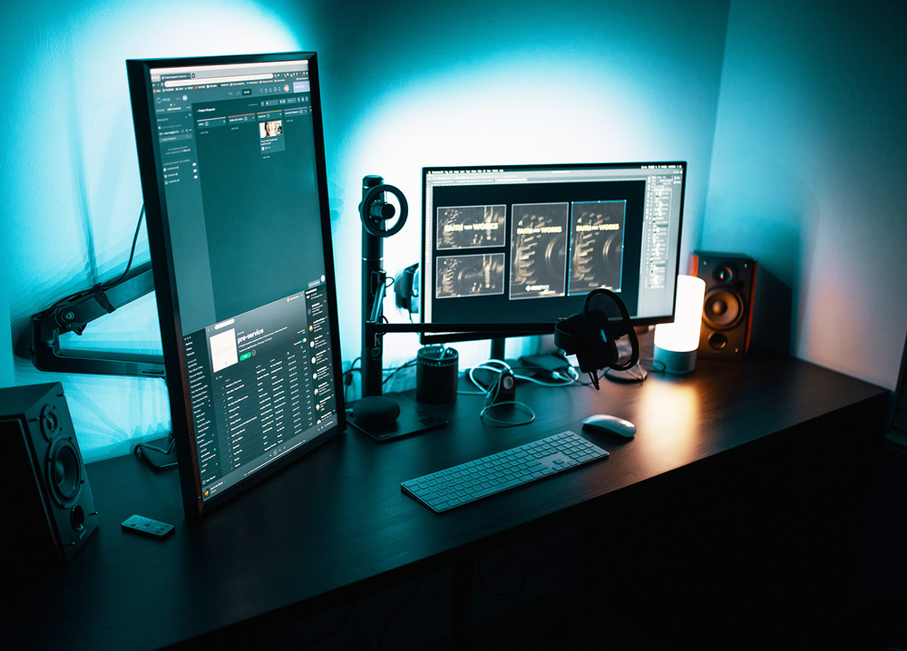 A computer desk with two monitors , a keyboard , mouse and speakers.