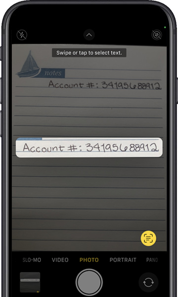 A cell phone is taking a picture of a notepad with the account number written on it.