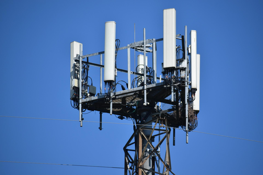 A telephone pole with a lot of antennas on it against a blue sky.