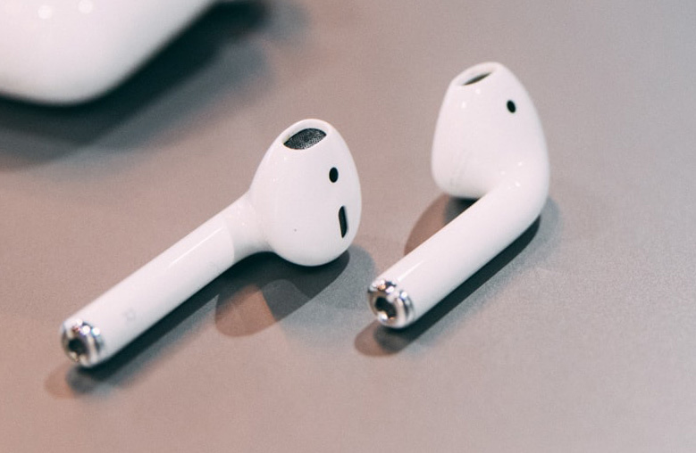 A pair of white airpods are sitting on a table.