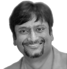 A man with a beard is smiling in a black and white photo.