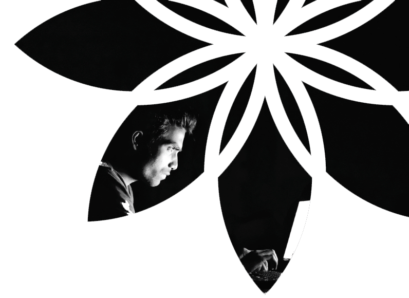 A black and white photo of a man behind a flower