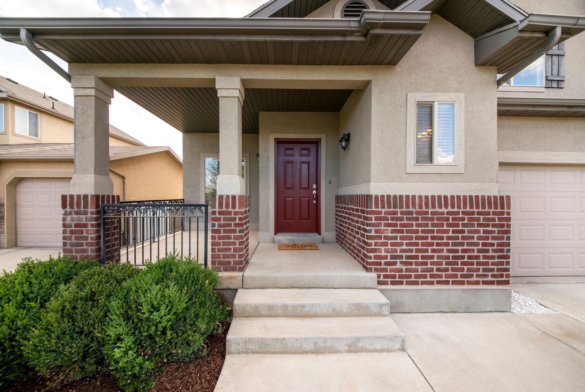 Front exterior of a house with a red door, brick facade, and covered porch.