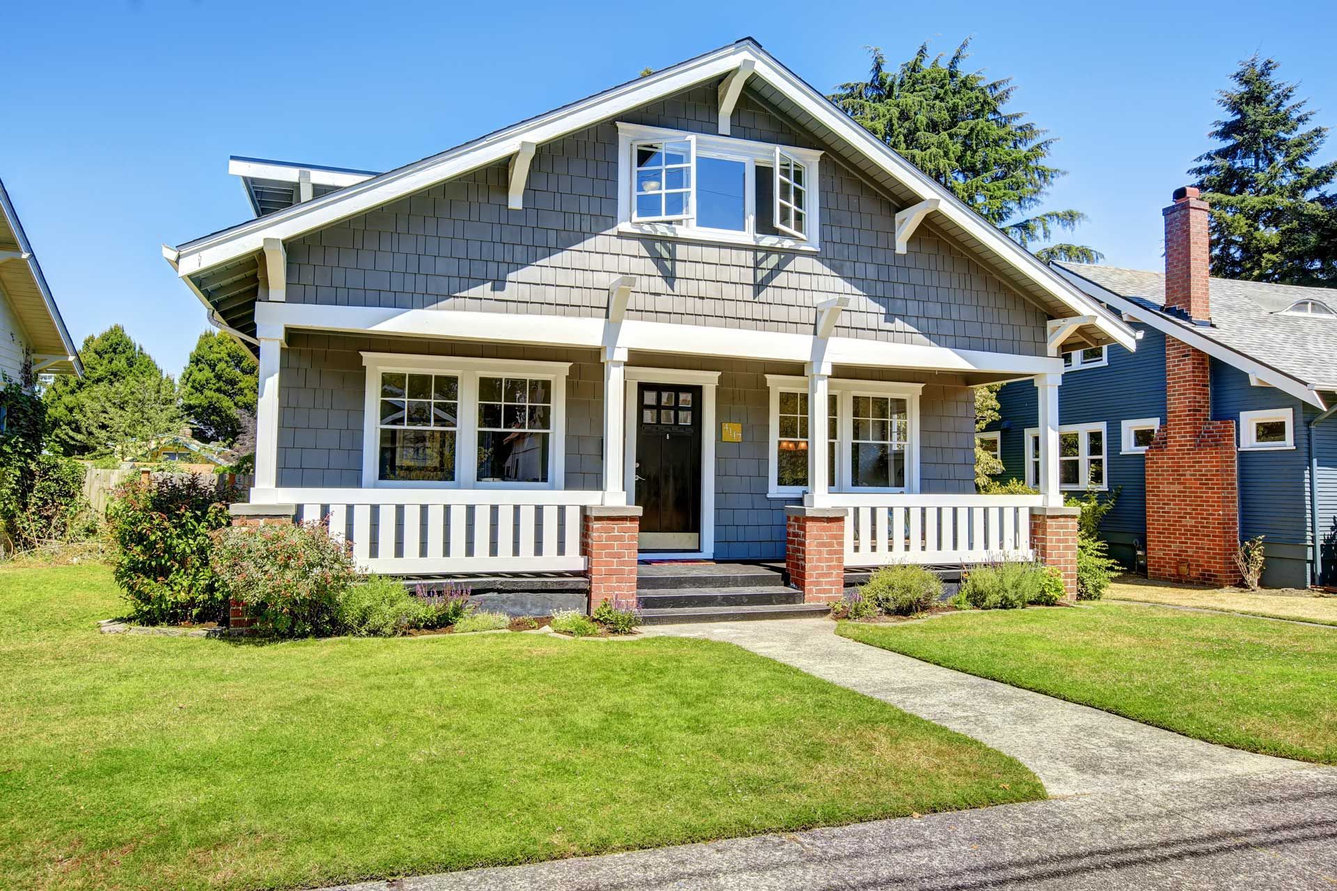 Gray Craftsman house with white trim, porch, and walkway, set on a green lawn.