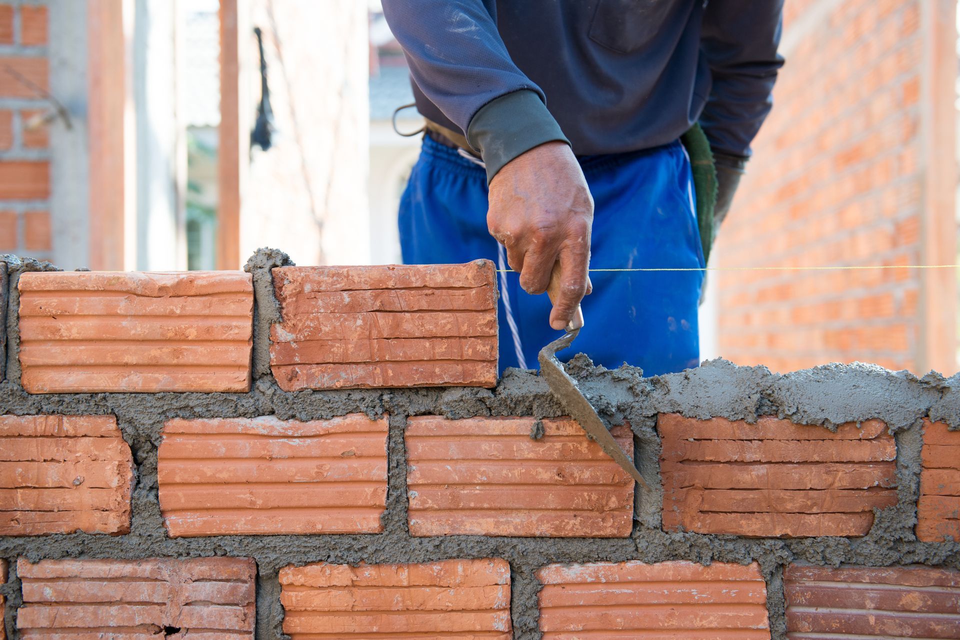 Construction worker laying bricks using a trowel, creating a wall. Construction worker laying bricks using a trowel, creating a wall.